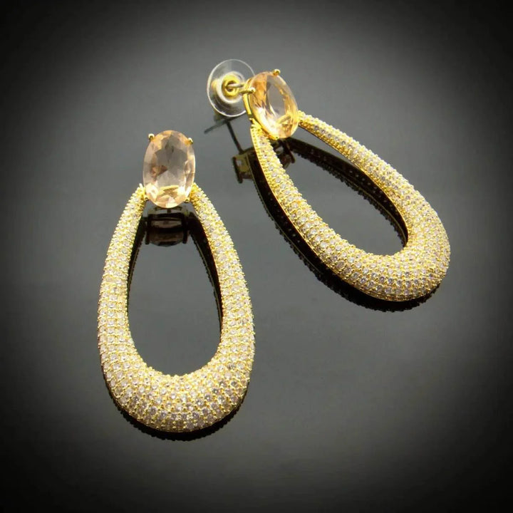 Long gold-colored drop earrings with zirconia